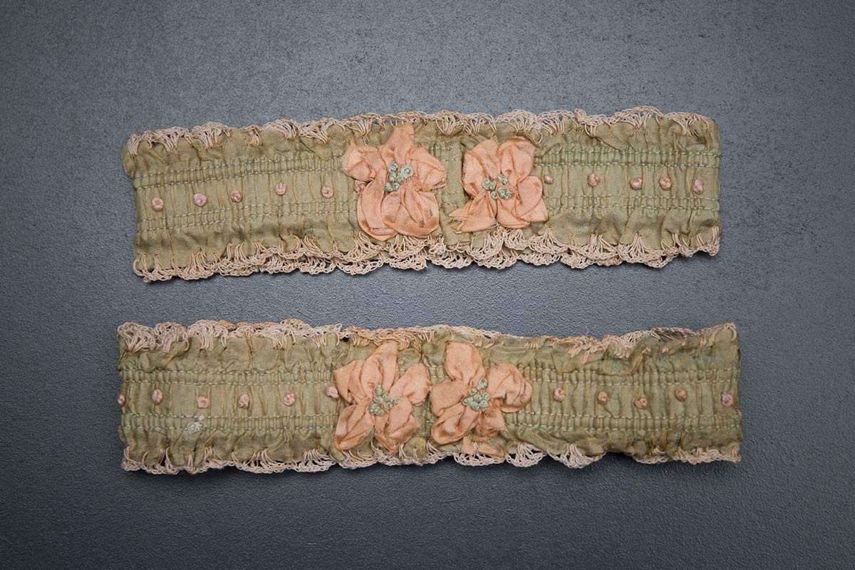 Green ribbon garters with crochet trim and French knot embroidery, 1920s, USA Photography by Tigz Rice Studios. From The Underpinnings Museum collection.