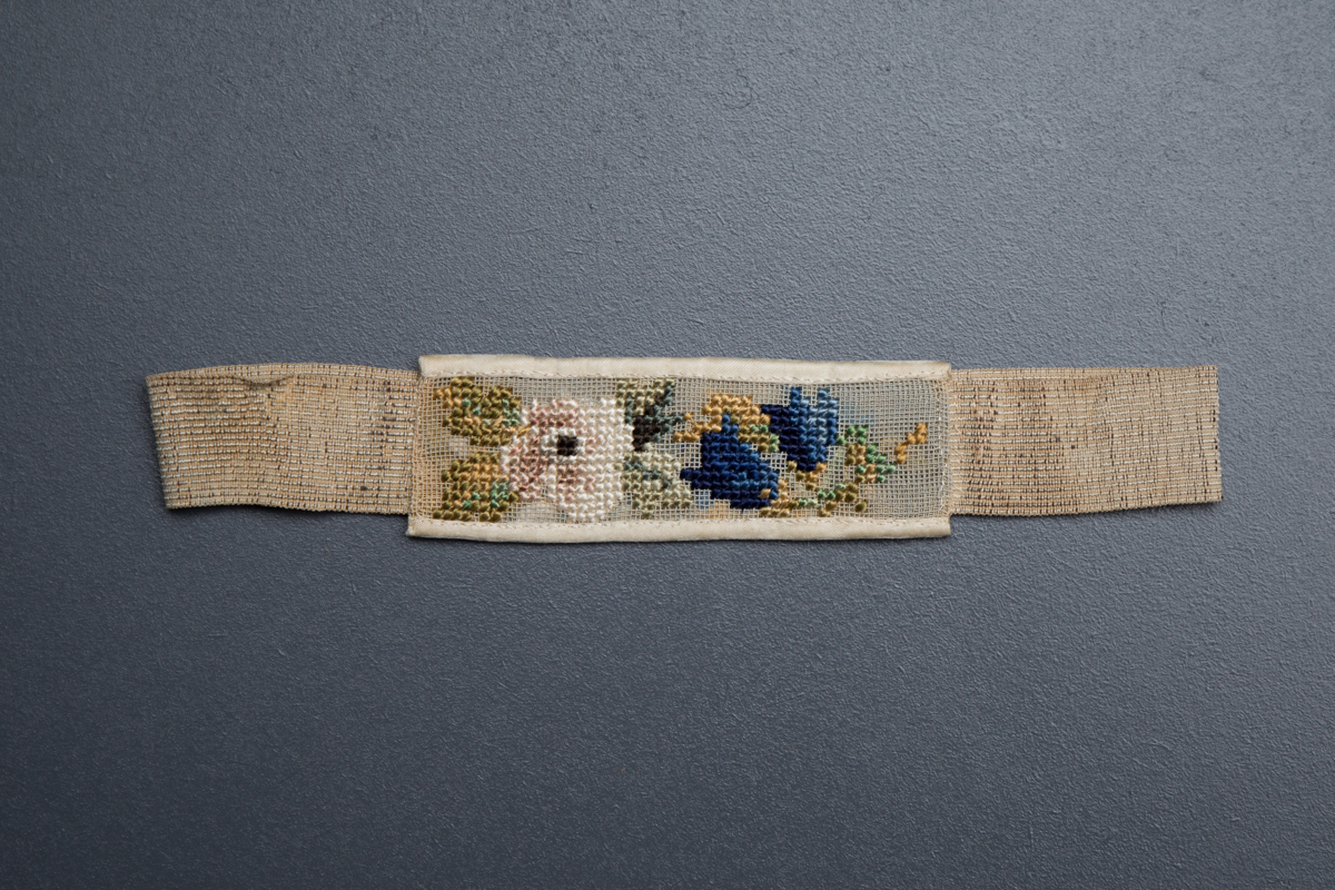 Cross stitch wedding garter, belonged to Mrs Clara Jane Wreford-Brown, 1864, Great Britain. From The Underpinnings Museum collection. Photography by Tigz Rice.