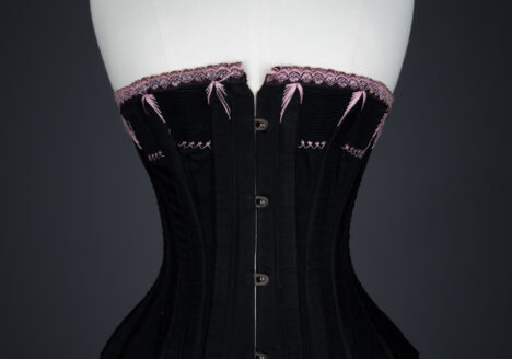 Black Cotton Corset With Spoon Busk, Pink Flossing Embroidery & Woven Trim, c. 1890-1900s, Great Britain. The Underpinnings Museum. Photography by Tigz Rice.