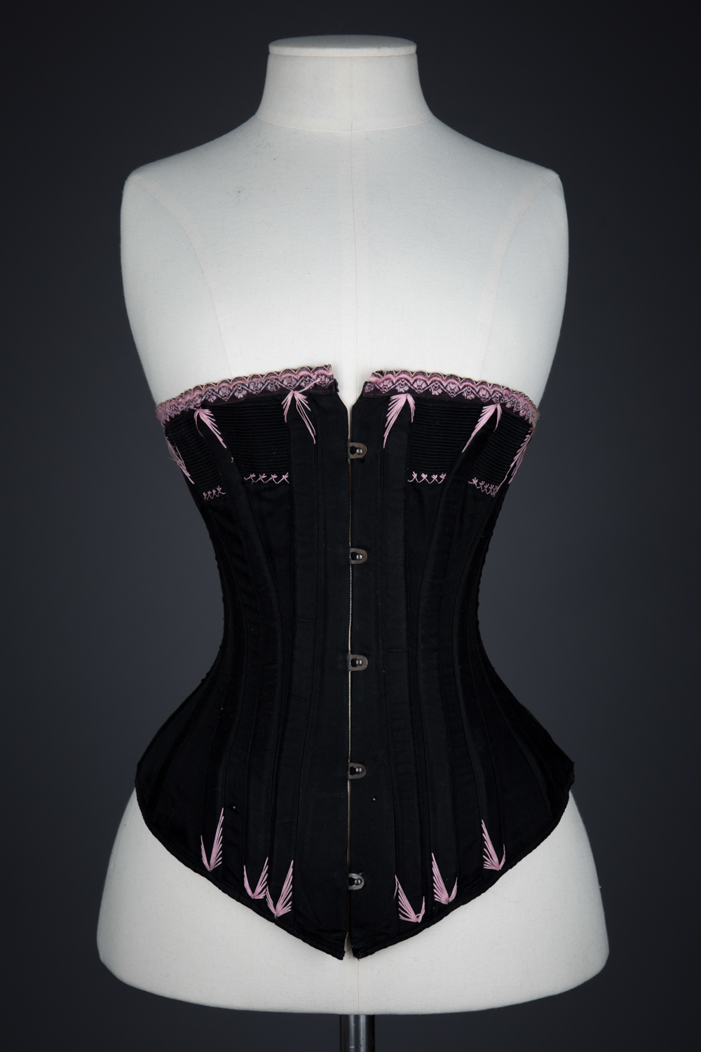 Black Cotton Corset With Spoon Busk, Pink Flossing Embroidery & Woven Trim, c. 1890-1900s, Great Britain. The Underpinnings Museum. Photography by Tigz Rice.