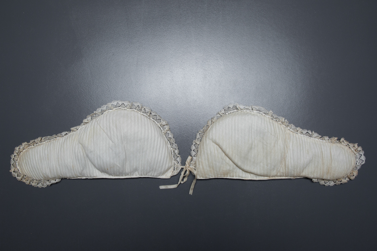 Cotton Padded Bust Improver With Lace Trim, c. 1880-1900s. The Underpinnings Museum. Photography by Tigz Rice.