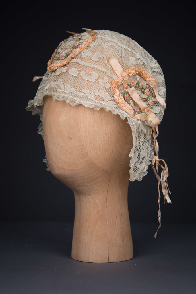 Cream Machine Lace Boudoir Cap With Silk Ribbonwork & Wired Ear Covers, c. 1920s, Great Britain. The Underpinnings Museum. Photography by Tigz Rice