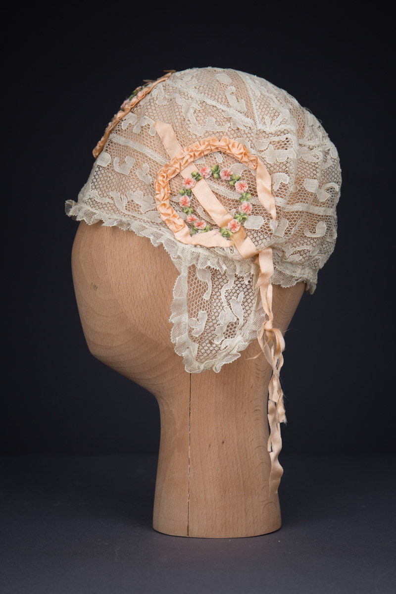 Cream Machine Lace Boudoir Cap With Silk Ribbonwork & Wired Ear Covers, c. 1920s, Great Britain. The Underpinnings Museum. Photography by Tigz Rice