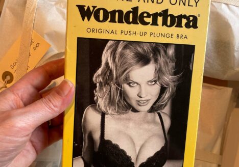 Image shows a hand holding a box for a Wonderbra. The box is yellow and has a black and white photograph on the front of a model wearing the bra