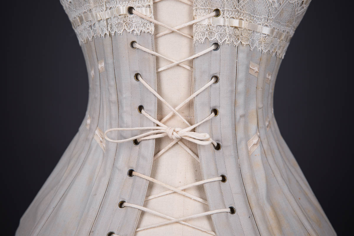 Grey Herringbone Coutil Corset With Ribbon Slot Lace Trim & Woven Ribbon Embellishment By Corset Cigno, c. 1900s, Italy. The Underpinnings Museum. Photography by Tigz Rice.