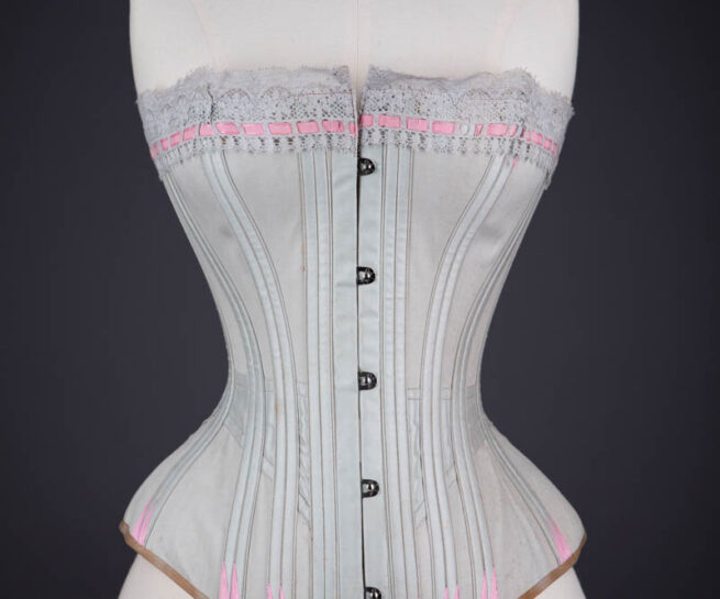 Grey Cotton Corset With Contrast Pink Flossing Embroidery And Lace Ribbon Slot Trim By Fitu Corsets, c. 1900s, Great Britain. The Underpinnings Museum. Photography by Tigz Rice.