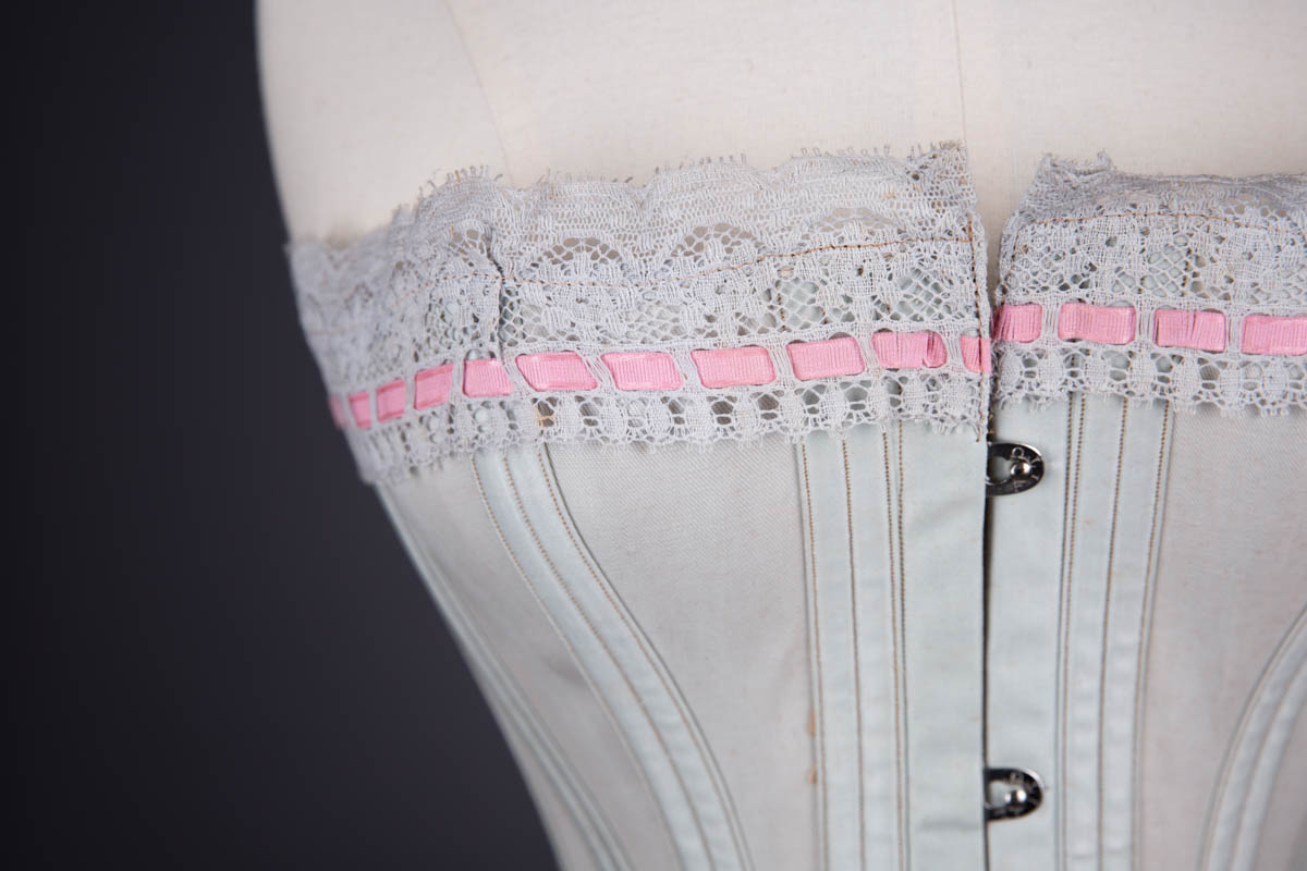 Grey Cotton Corset With Contrast Pink Flossing Embroidery And Lace Ribbon Slot Trim By Fitu Corsets, c. 1900s, Great Britain. The Underpinnings Museum. Photography by Tigz Rice.